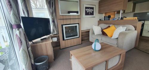 a living room with a couch and a fireplace at Holiday Home at Combe Haven, St Leonards, Hastings in St. Leonards