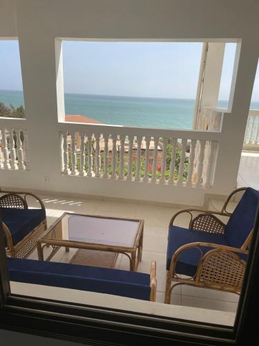a balcony with chairs and a table and a view of the ocean at Villa Vista in Toubab Dialaw