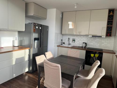 une cuisine avec des armoires blanches et une table et des chaises dans l'établissement Duplex cosy proche de Paris, à Bezons