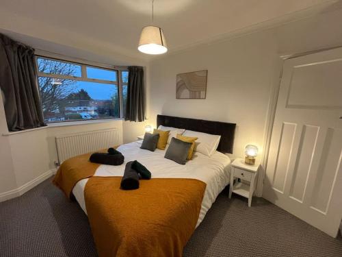 a bedroom with a large bed and a window at Cosy & Comfortable 3 Bed House, Office & Driveway in London