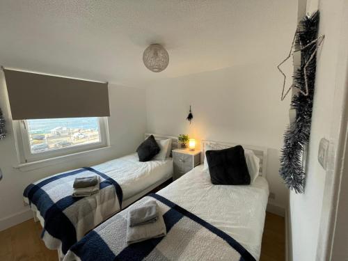 two beds in a room with a window at Largs 2 bedroom Apartment in Largs