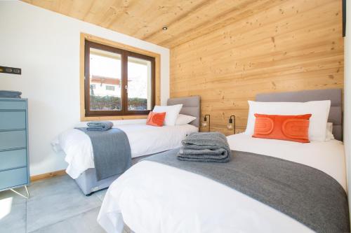 deux lits dans une chambre aux murs en bois dans l'établissement Contemporary 2 bed apartment in central Morzine, à Morzine