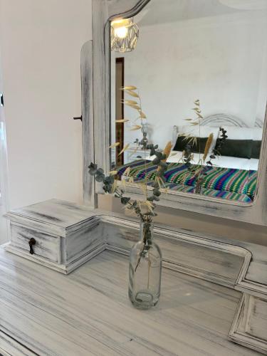 a vase with flowers sitting on a table in front of a mirror at A Casa da Praça in Vila Viçosa