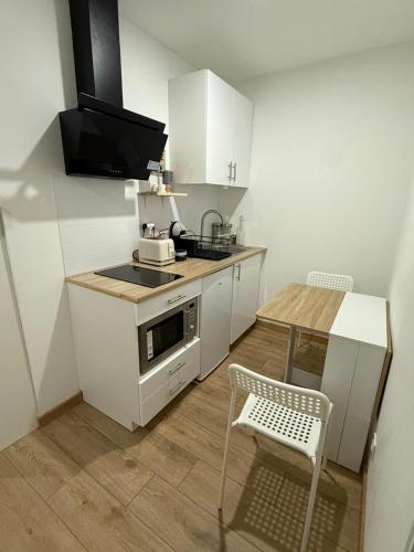 une cuisine avec des armoires blanches, une table et un micro-ondes dans l'établissement Le Cosy, à Rochefort