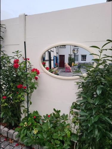 a circular mirror on a white wall with flowers at NY-GOLDEN APARTMENTS-Dortmund Airport in Dortmund