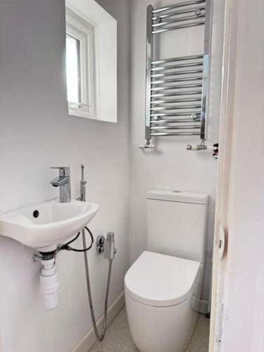 a white bathroom with a toilet and a sink at Cosy 4-Bedroom Entire Home - Sleeps 7, Oxford in Oxford