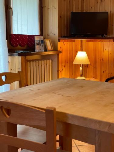 a table with a lamp and a television in a room at Case Vacanza Perron in Sauze dʼOulx