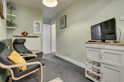 a living room with two chairs and a flat screen tv at The Old Bike Cabin Flat 1 in Heapey