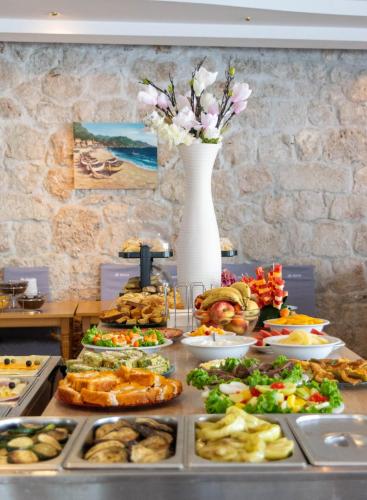 a buffet with a table full of food and a vase of flowers at Beach Hotel in Drasnice