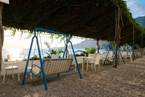 a swing on a beach with chairs and the ocean at Beach Hotel in Drasnice