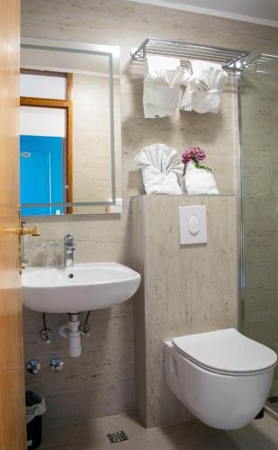 a bathroom with a sink and a toilet and a mirror at Beach Hotel in Drasnice