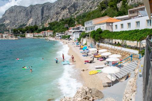 a beach with umbrellas and people in the water at Beach Hotel in Drasnice