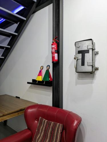 a red chair next to a table with a t sign on a wall at VilafraggleRock, casa de diseño moderno en Pontedeume in Puentedeume