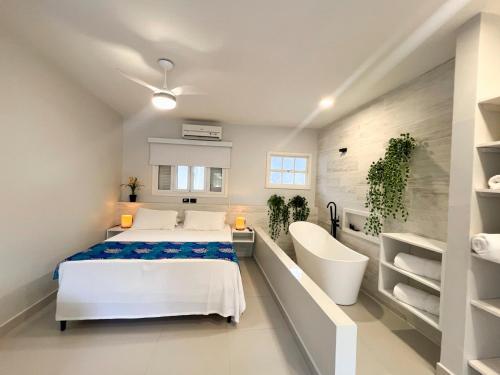 a white bedroom with a bed and a white chair at Pousada Camburioca in Camburi