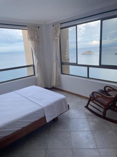 a bedroom with large windows and a bed and a chair at Apartamento frente al mar en el Rodadero in Gaira