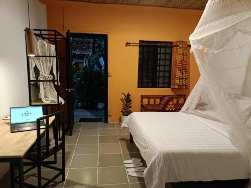 a bedroom with a bed and a desk with a laptop at Madam Sokha Homesteading in Siem Reap