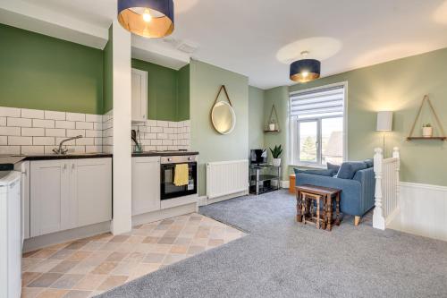 a kitchen and living room with green walls and a blue couch at The Old Bike Shop Flat 2 in Heapey
