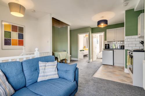 a living room with a blue couch and a kitchen at The Old Bike Shop Flat 2 in Heapey