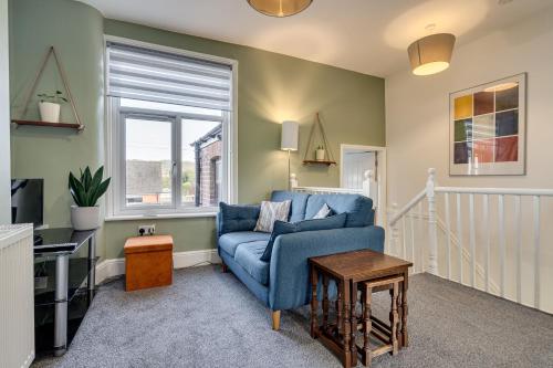 a living room with a blue couch and a window at The Old Bike Shop Flat 2 in Heapey