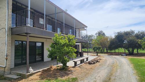 a building with a tree next to a dirt road at Bahwidgee Lodge - Riverside Retreat in Tumut