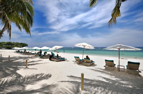 a group of people sitting on a beach with umbrellas at Henann Resort Alona Beach in Panglao