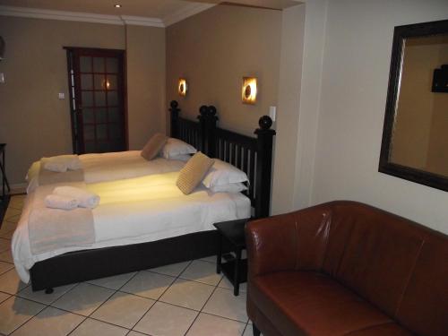 a bedroom with a bed and a chair and a couch at Njala Guest House in Middelburg