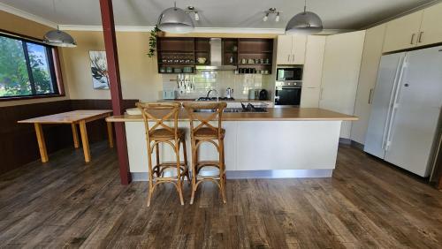a kitchen with a counter and two bar stools at Bahwidgee Lodge - Riverside Retreat in Tumut