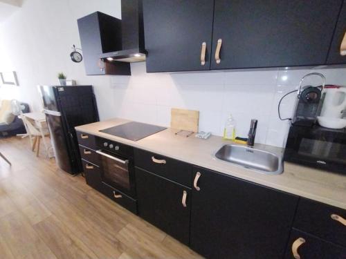 La cuisine est équipée de placards noirs, d'un évier et d'un réfrigérateur. dans l'établissement Sur le Vieux Port , Appartement 50m2, 4pers, à Marseille