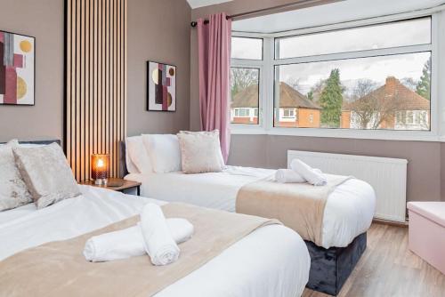 two beds in a room with a window at Enchanting 4 spacious bedrooms in Birmingham
