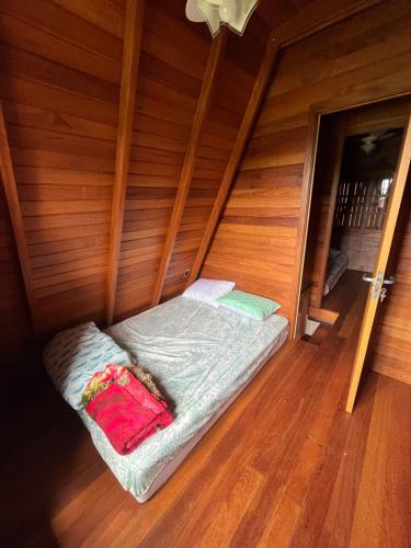 a small bed in a room with wooden walls at Cabanas Abedon in Garopaba