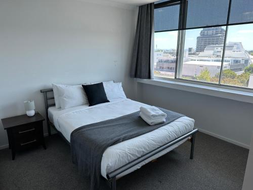 a bed in a room with a large window at Corporate Accommodation - Modern CBD Apartment in Hamilton