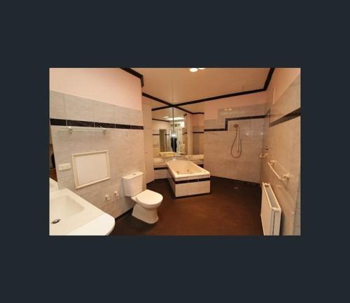 a bathroom with a toilet and a tub and a sink at Art House On The Park in Melbourne