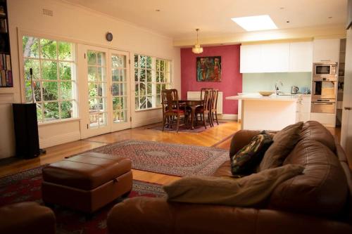 a living room with a brown couch and a kitchen at Art House On The Park in Melbourne