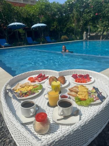 a table with plates of food next to a swimming pool at New Mekar Jaya Hotel in Legian
