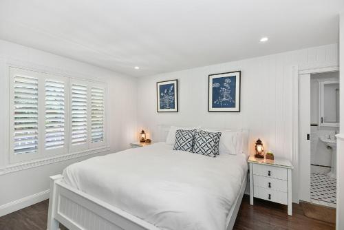 a white bedroom with a large bed and windows at Margaret's Hamptons Beach House in Hawks Nest