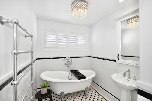 a white bathroom with a tub and a sink at Margaret's Hamptons Beach House in Hawks Nest