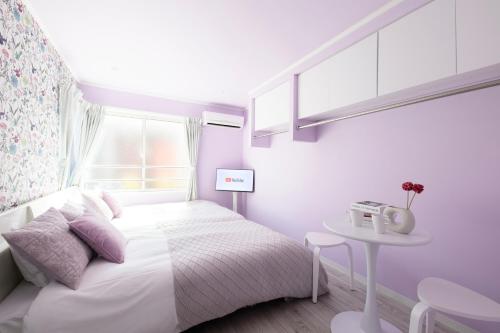 a white bedroom with a bed and a table at スカイフィール大久保 in Tokyo