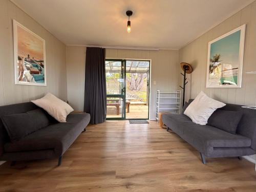 a living room with two couches and a sliding glass door at Driftwood Retreat in Tutukaka