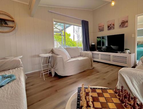 a living room with a chess board in the middle at Driftwood Retreat in Tutukaka