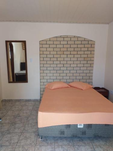 a bed in a bedroom with a brick wall at Cantinho do silêncio in Joinville