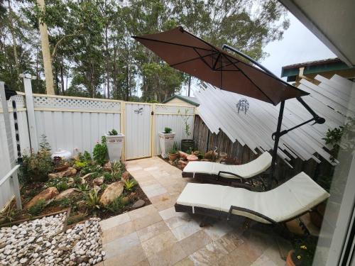 a patio with two chairs and an umbrella at House by Lavender Lane - Forest Views, FREE Parking in Cessnock