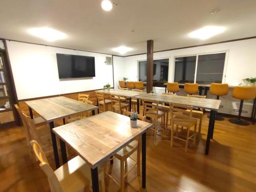 a room with tables and chairs and a flat screen tv at Hakuba Norikura Wakaguri Guesthouse in Otari