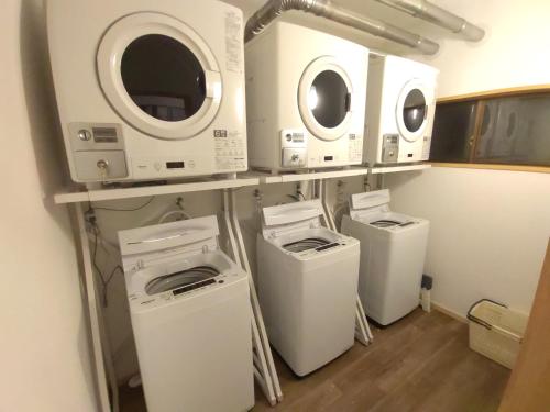 a laundry room with three washing machines and washers at Hakuba Norikura Wakaguri Guesthouse in Otari