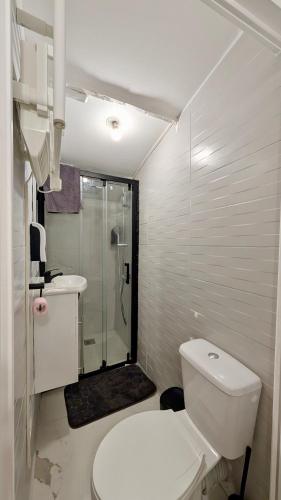 une salle de bain blanche avec toilettes et douche dans l'établissement Kalyvia-calme & résidentiel- Proxy Paris, à Houilles