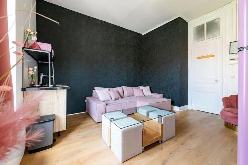 un salon avec un canapé violet et une table dans l'établissement Les Appart'Hôtels Du Calaisis - Pinky Terrasse 103, à Calais