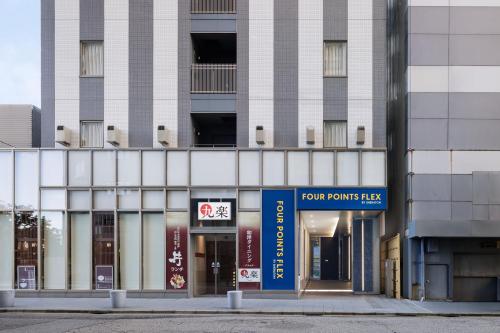 金沢市にあるフォーポイント フレックス by シェラトン 金沢の正面に看板がある背の高い白い建物