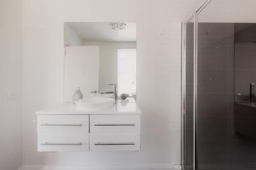 Un baño blanco con lavabo y ducha en Modern Home in Sandy Bay - Sleeps 8 Guests, en Sandy Bay