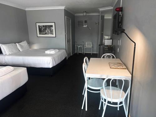 a hotel room with two beds and a table and chairs at Old Maitland Inn - Rutherford in Maitland