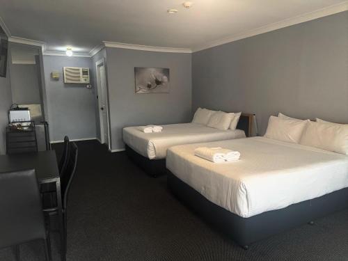 a hotel room with two beds with white sheets at Old Maitland Inn - Rutherford in Maitland