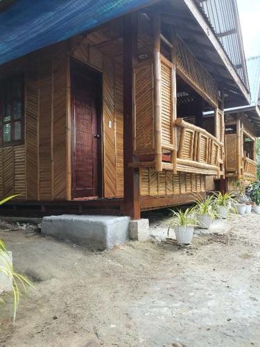 a wooden house with a porch and some plants at MarineroTravellers Inn in San Vicente